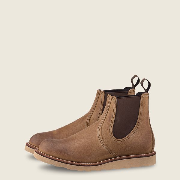 Brown leather Chelsea boots with elastic sides and pull tabs on neutral background