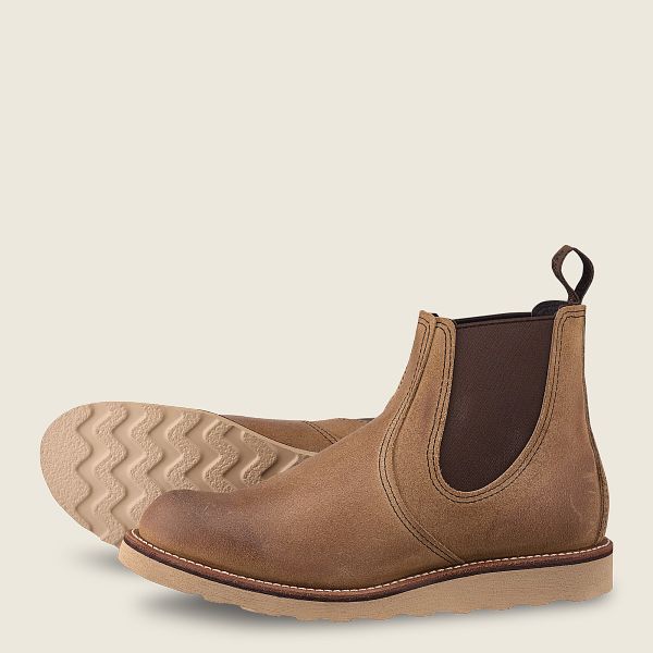 Tan leather Chelsea boots with brown elastic side panels and beige rubber soles on light background